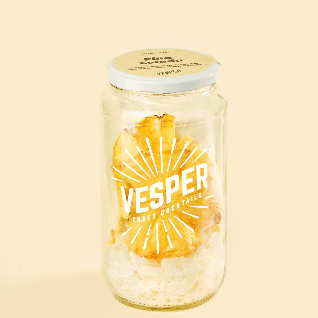 Vesper cocktail jar with pineapple chunks on a beige background