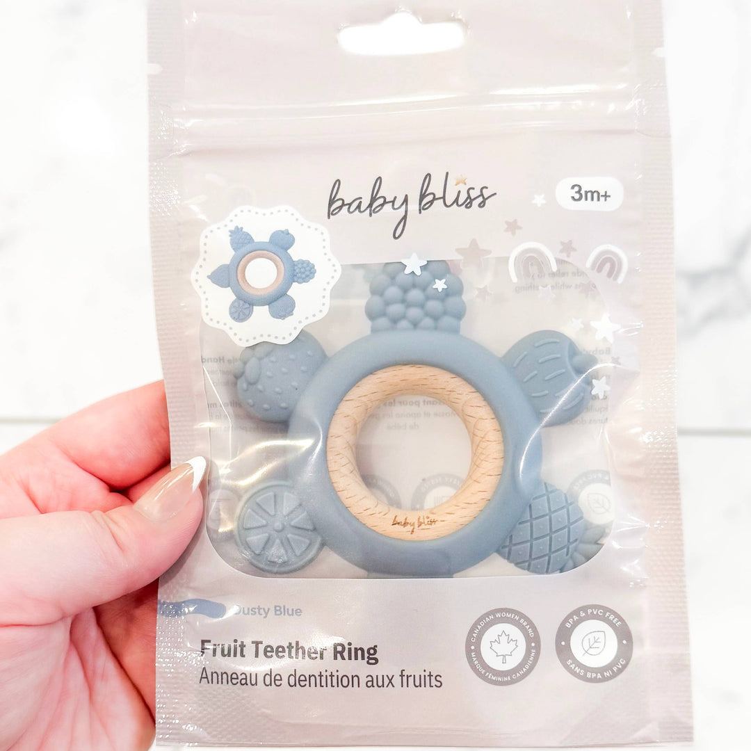 Hand holding a baby teether ring packaging with &