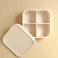 Beige compartmentalized food container with lid on a beige background