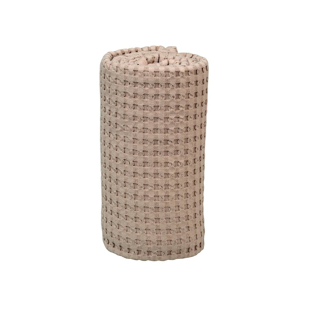 A rolled-up beige woven bath mat with a textured waffle pattern, shown on a plain white background.
