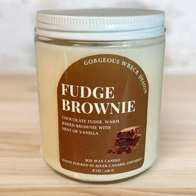A soy wax candle in a clear glass jar with a white lid, labeled &