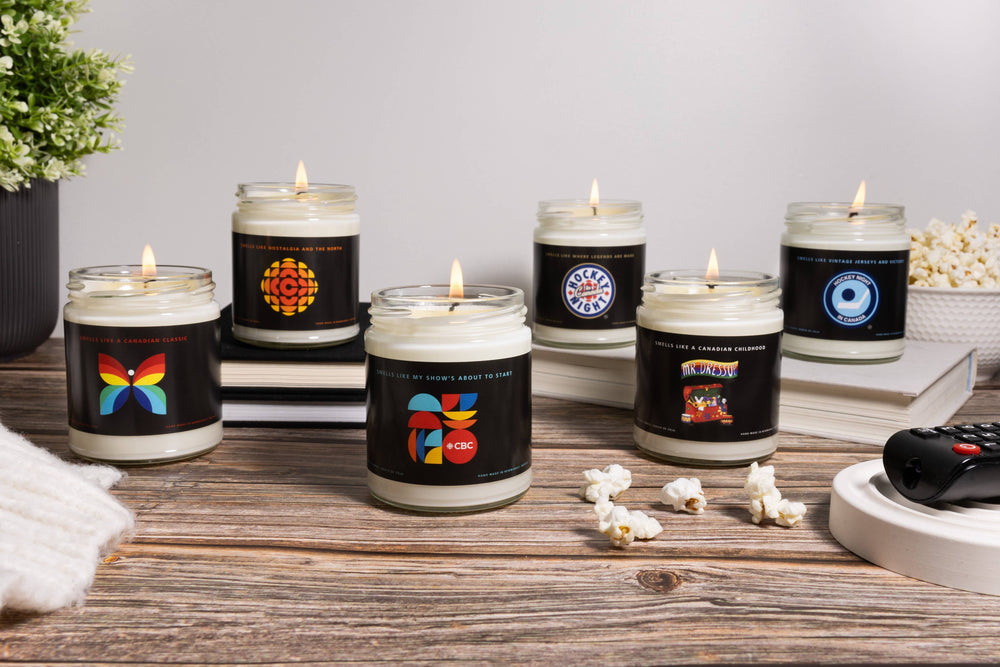 Set of candles with various designs on black labels arranged on a wooden surface.