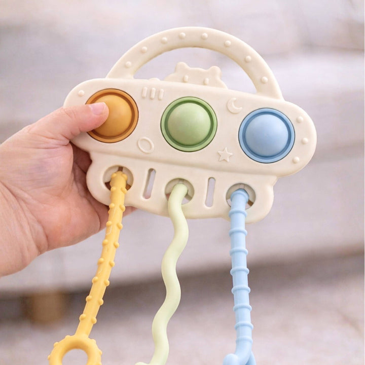 Hand holding a baby teething toy with colorful buttons and textures.