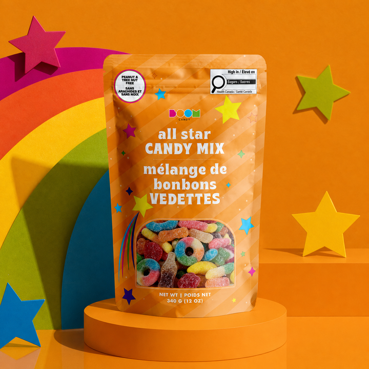 A stand-up pouch of All Star Candy Mix displayed on a round pedestal against a bright orange background with rainbow arches and star cutouts. The package is orange with multicolored star graphics and a clear window showing colorful loop candy inside.