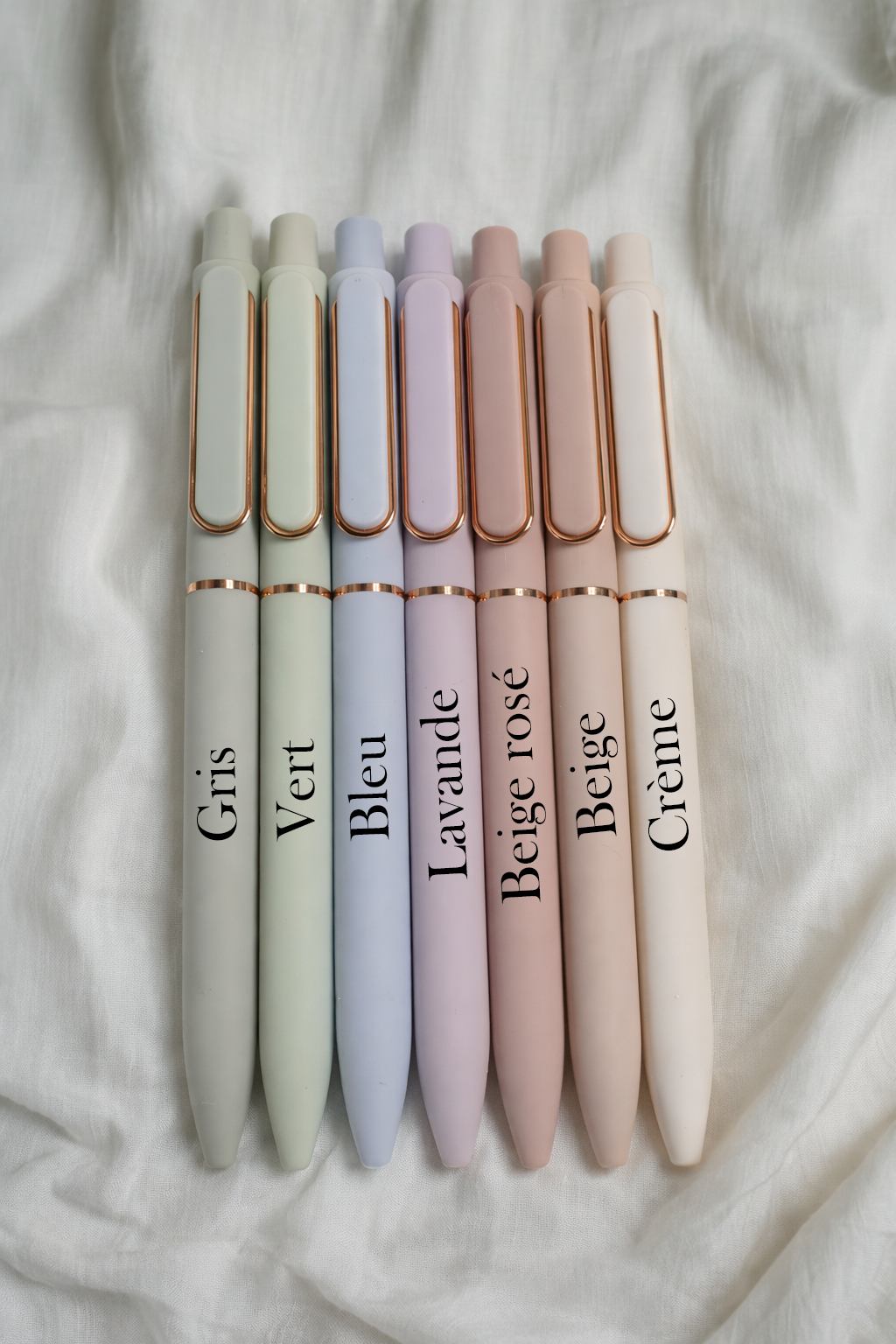 Set of pastel-colored pens with names on a soft fabric background