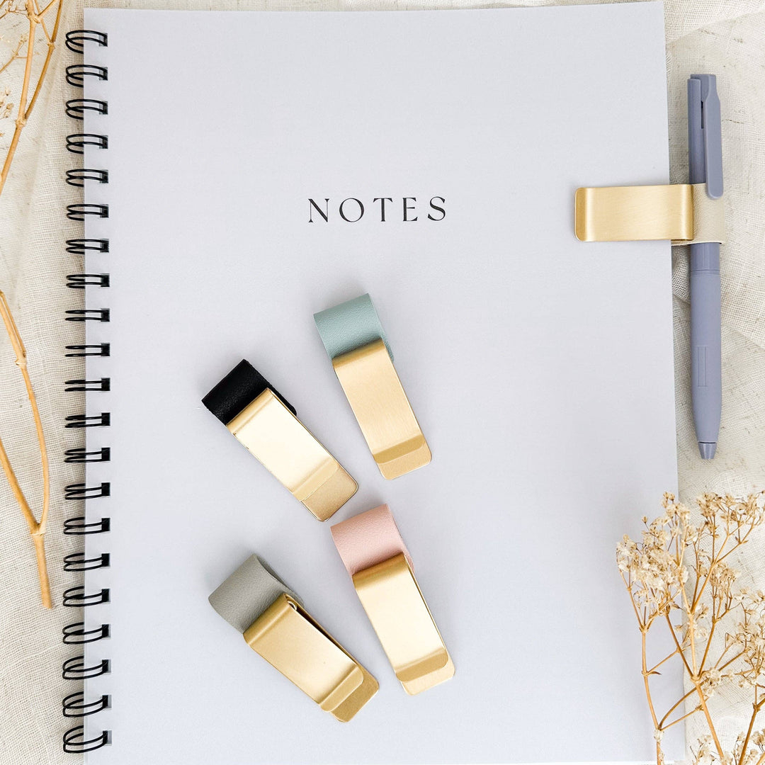 Notebook with decorative flags and a pen on a light surface