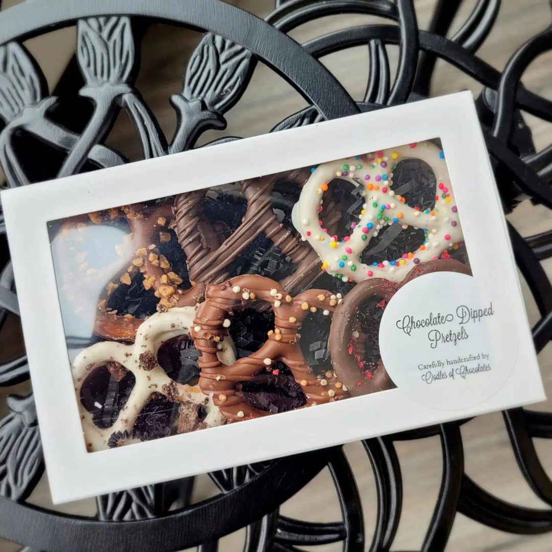 Box of chocolate-dipped pretzels with sprinkles on a decorative metal surface