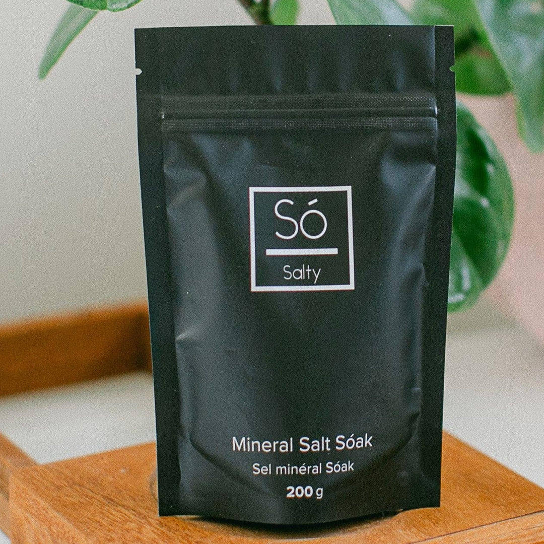Black package labeled 'Sö Salty' on a wooden tray with a plant in the background