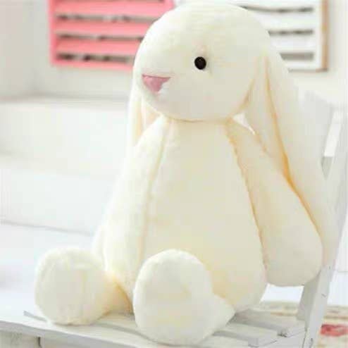 White plush bunny sitting on a white chair with a blurred background