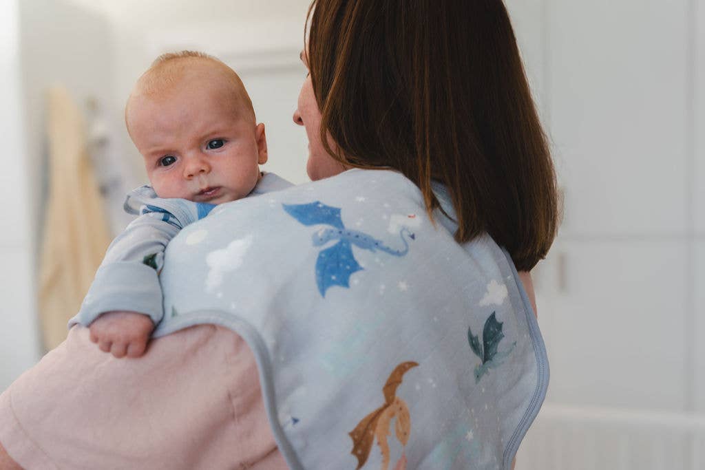 Woman holding a baby wrapped in a colorful blanket with animal patterns.