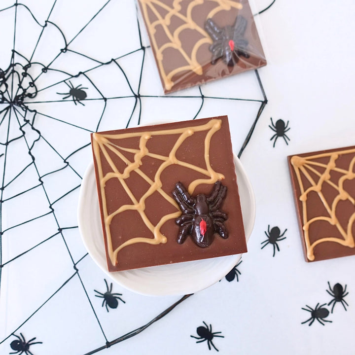 Chocolate bars with spider web and spider decorations on a white surface with spider web and spider designs.