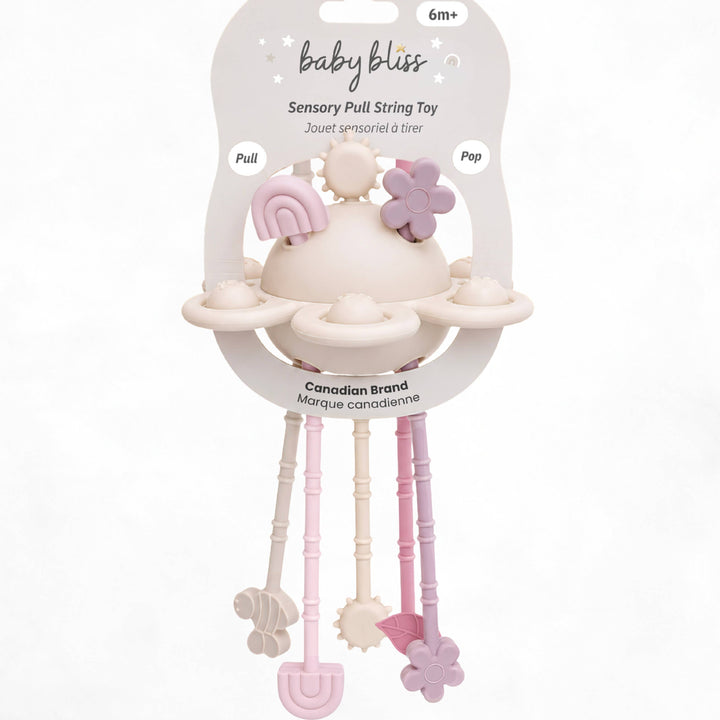 Baby Bliss sensory pull string toy in its original packaging, featuring a cream-colored teething ring with pastel pink and lavender accents, and three dangling sensory bars in pink, cream, and lavender.