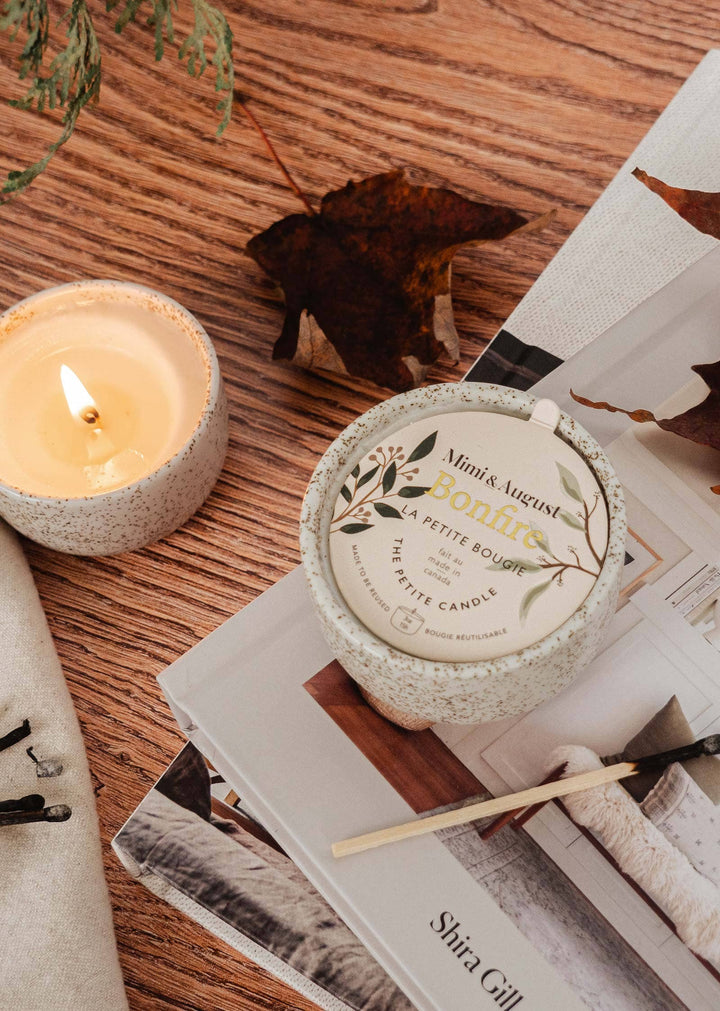 Candle and decorative container on a wooden surface with a magazine underneath