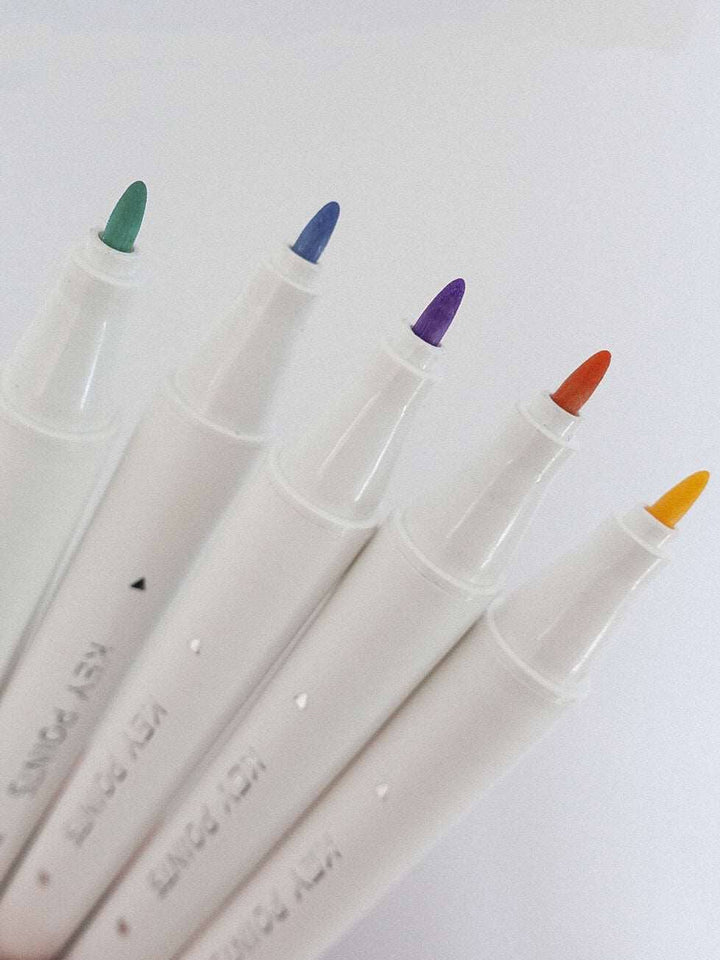 Five markers with colored caps on a white background