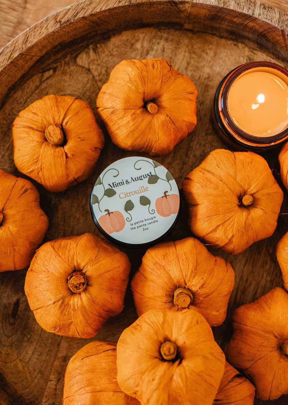 Candle with pumpkins on a wooden surface