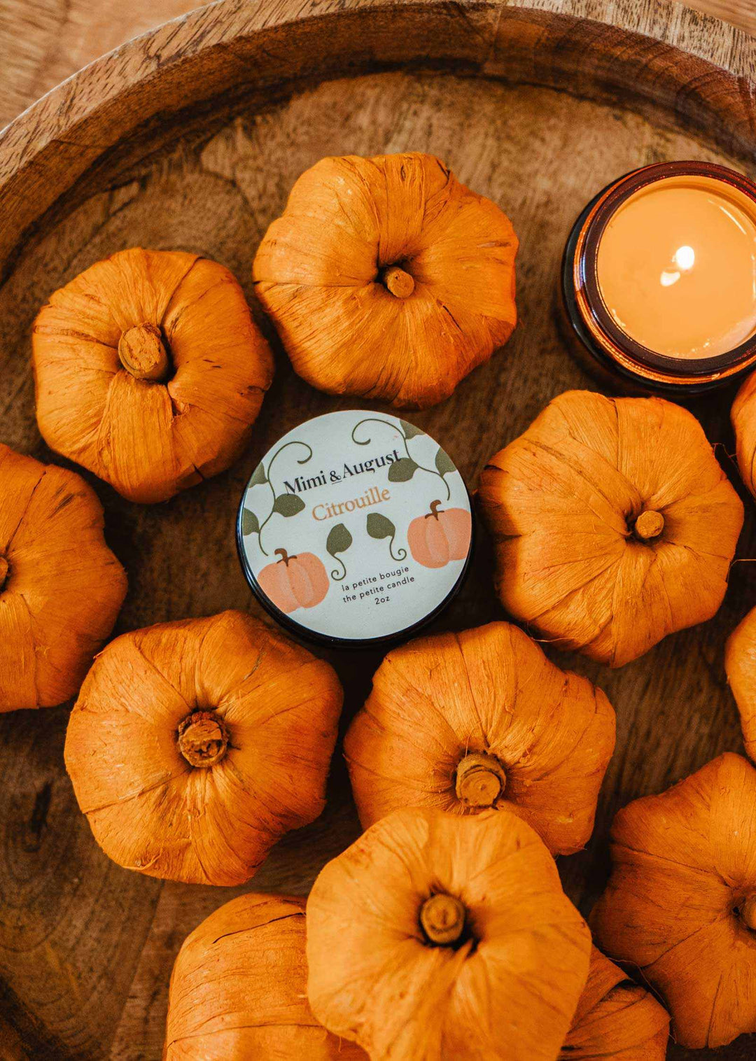 Candle with pumpkins on a wooden surface