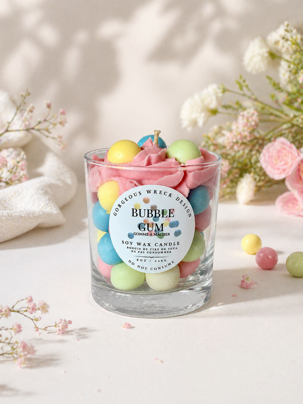 Candle with colorful bubbles in a glass jar on a light background