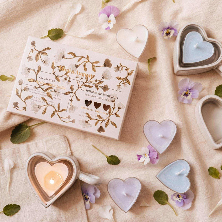 Heart-shaped candles and packaging on a soft fabric background with flowers.