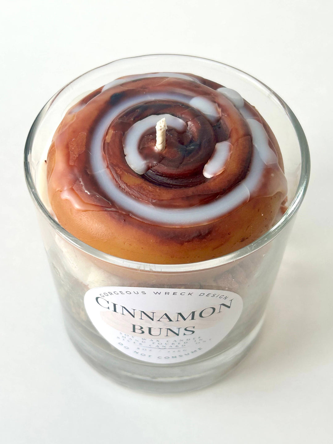 Candle in the shape of a cinnamon bun with a label on a white background