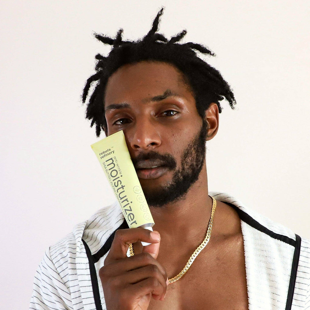 Man holding a tube of moisturizer against a white background