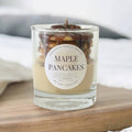 Candle with 'Maple Pancakes' label on a wooden surface