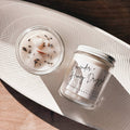 Crushed Candle Company Lavender + Honey Drizzle Candle with a white jar and lavender and honey-colored wax, set on a wooden surface