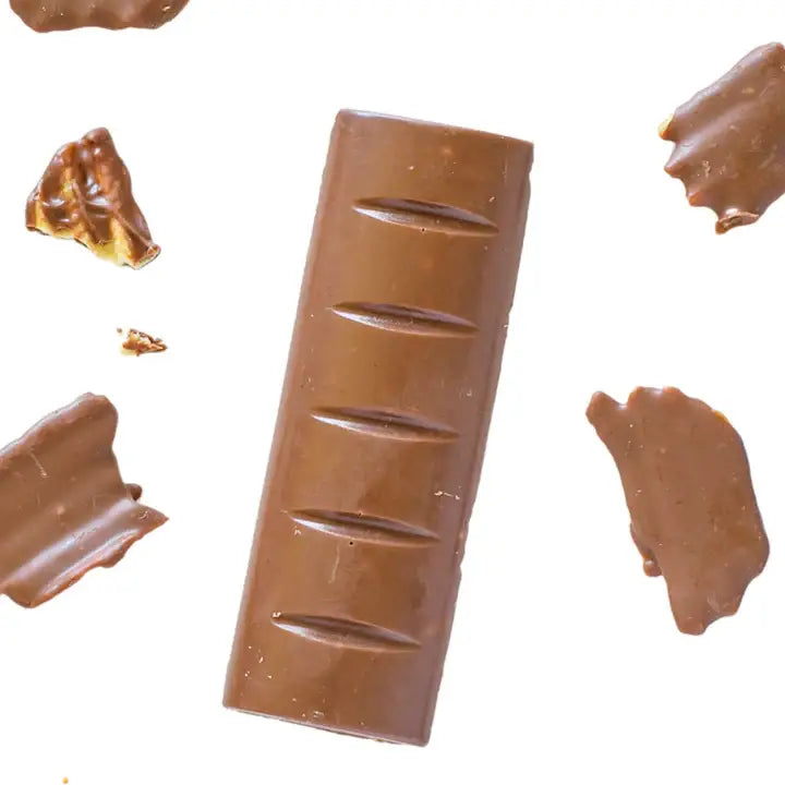 A milk chocolate bar with five scored bars, surrounded by scattered pieces of broken chocolate on a plain white background.