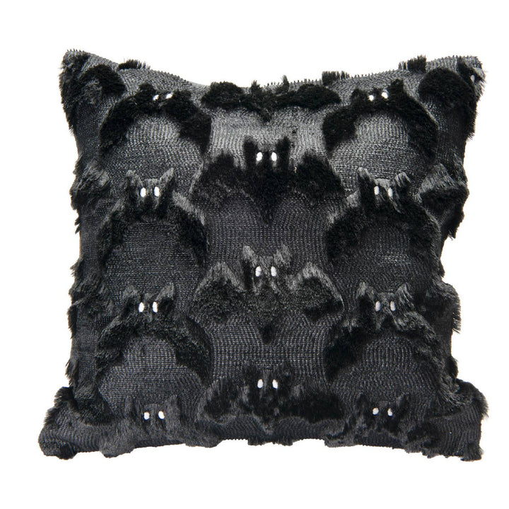 A square black throw pillow featuring a textured, raised pattern of stylized bat faces with small white bead eyes, set against a plain white background.