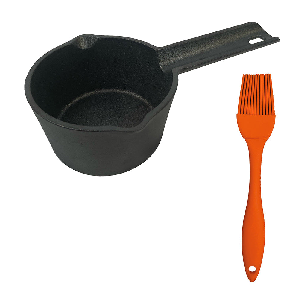 Black cast iron measuring cup and orange brush on a white background