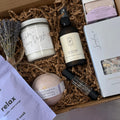 Collection of lavender-themed products in a box including a candle, bath tea, and bath bomb.