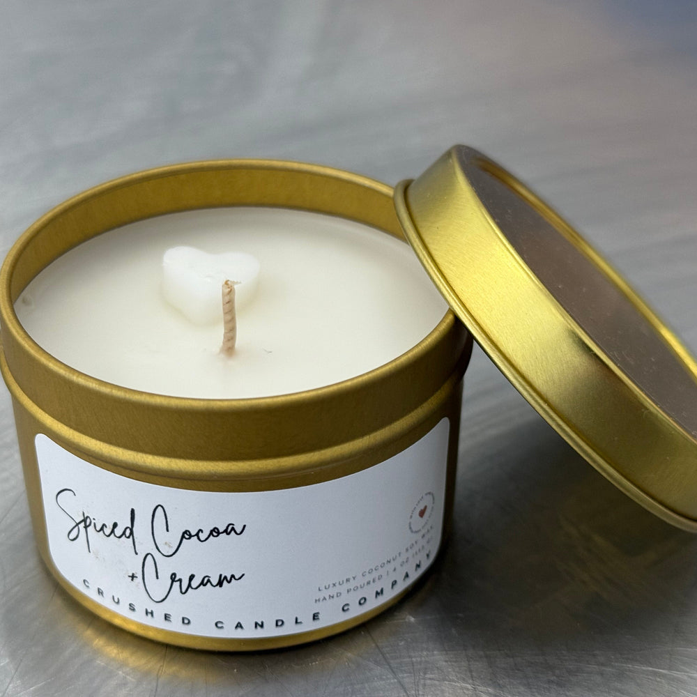 Candle in a gold tin with a label on a metallic surface