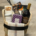 Gift basket with wine, snacks, and other items on a textured surface
