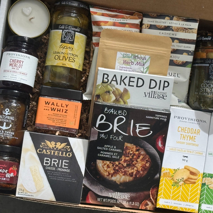Assorted food items including cheese, olives, and dips in a box packaging.