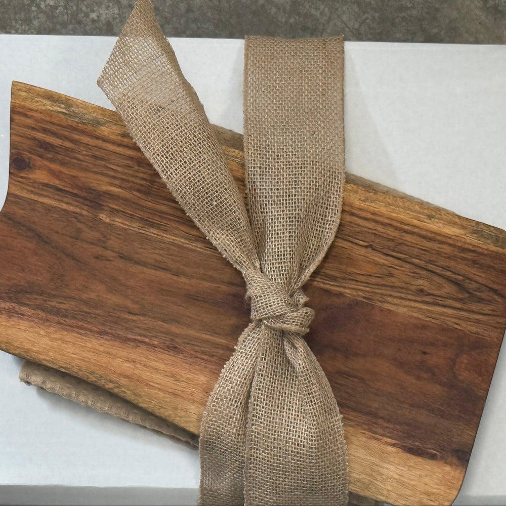 Wooden cutting board with a burlap ribbon on a white box against a gray background