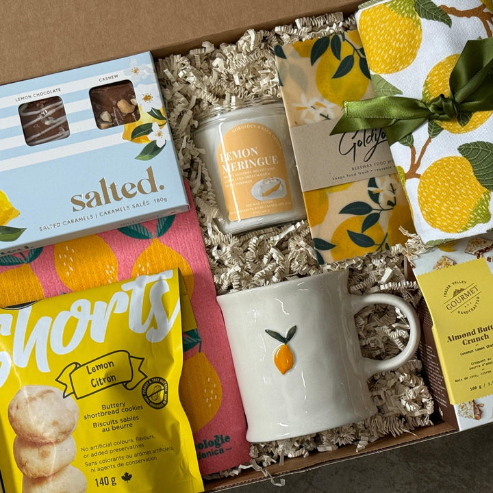 Gift box with lemon-themed products including a mug, snacks, and a candle.