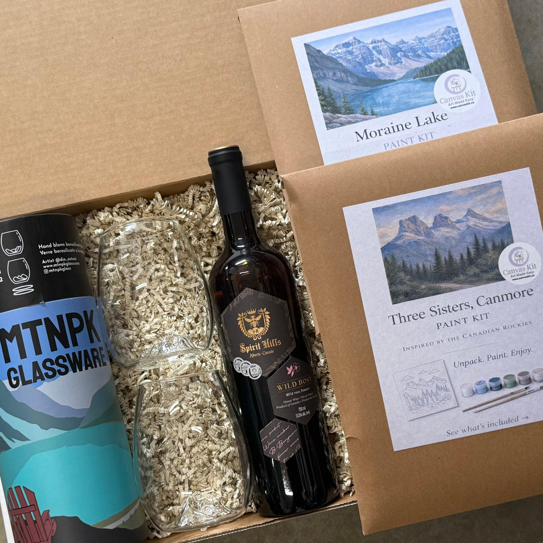 Box containing a bottle of wine, glassware, and paint kit with mountain-themed labels.