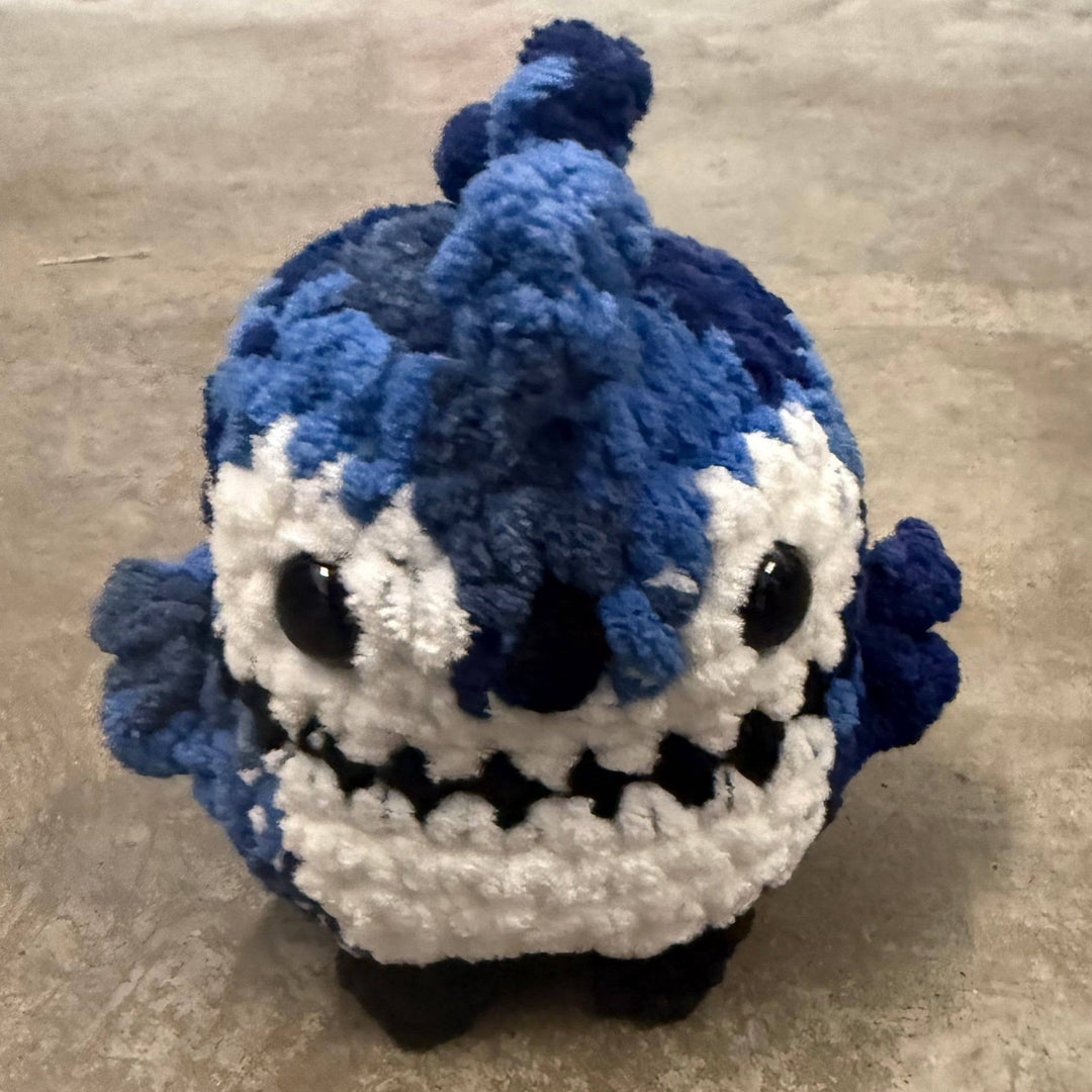 Crocheted blue and white creature on a textured surface