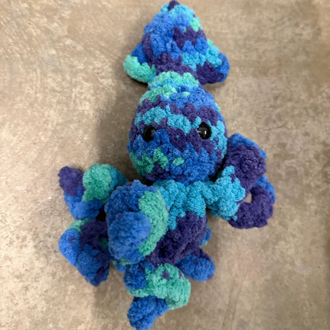 Blue and green knitted toy on a beige surface