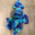 Blue and green knitted toy on a beige surface