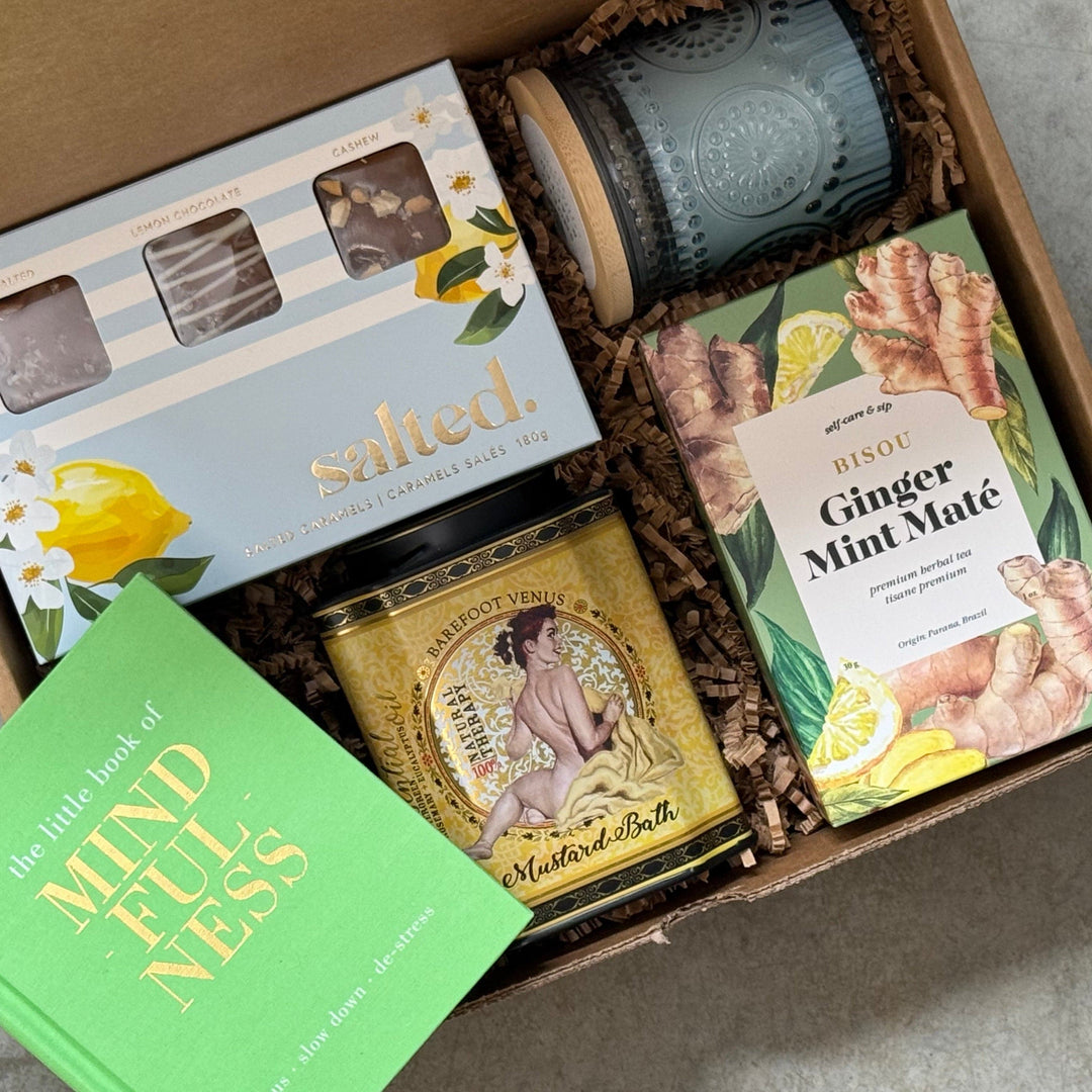 Gift box with candles, tea, and a book on a gray surface