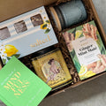 Gift box with candles, tea, and a book on a gray surface