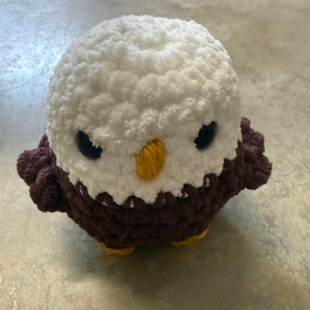 Small knitted or crocheted toy resembling a face on a textured surface
