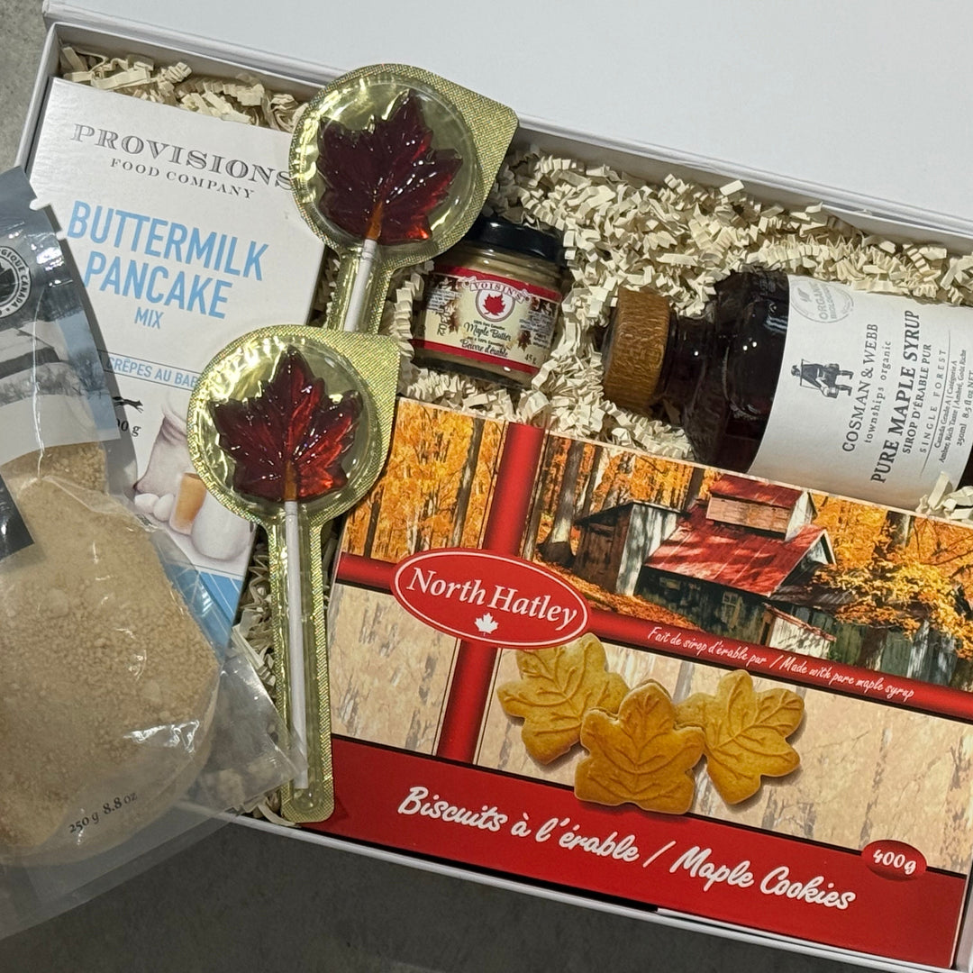 Gift box with maple syrup, cookies, and other items on a gray surface