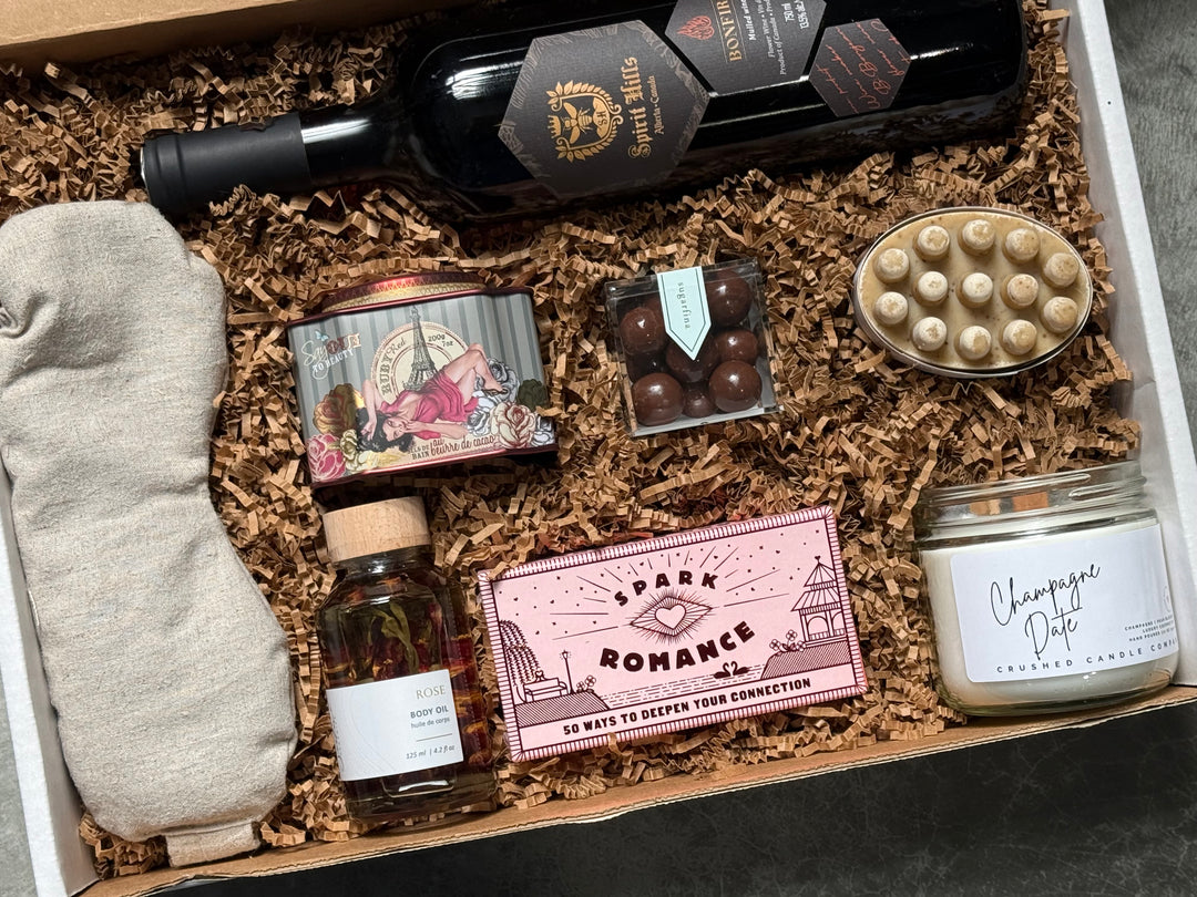 Gift box with wine, candles, and other items on a dark surface