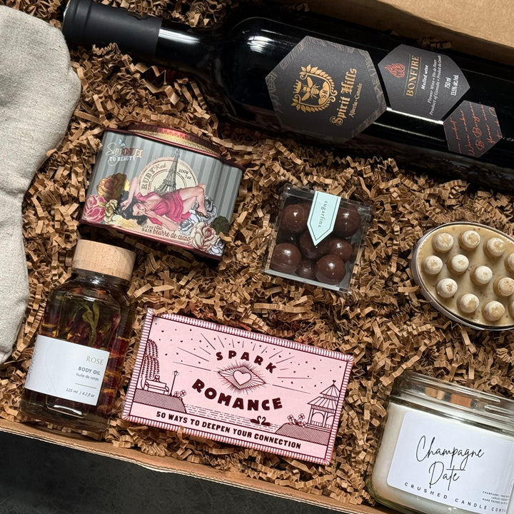 Gift box with wine, chocolate, and other items on a gray surface