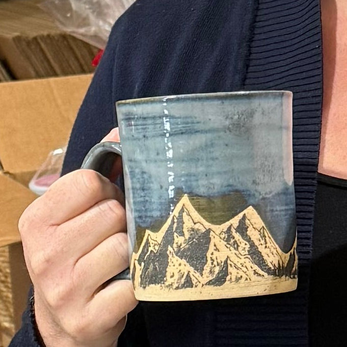 Woman holding two mugs with a warehouse background