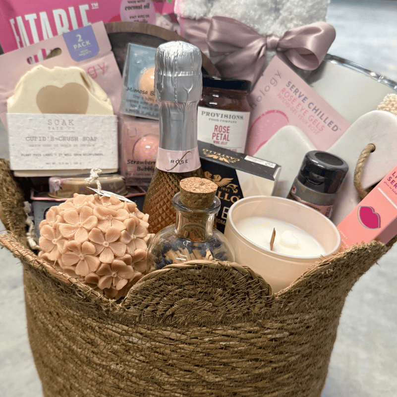 Gift basket with various items including candles and soaps on a light background