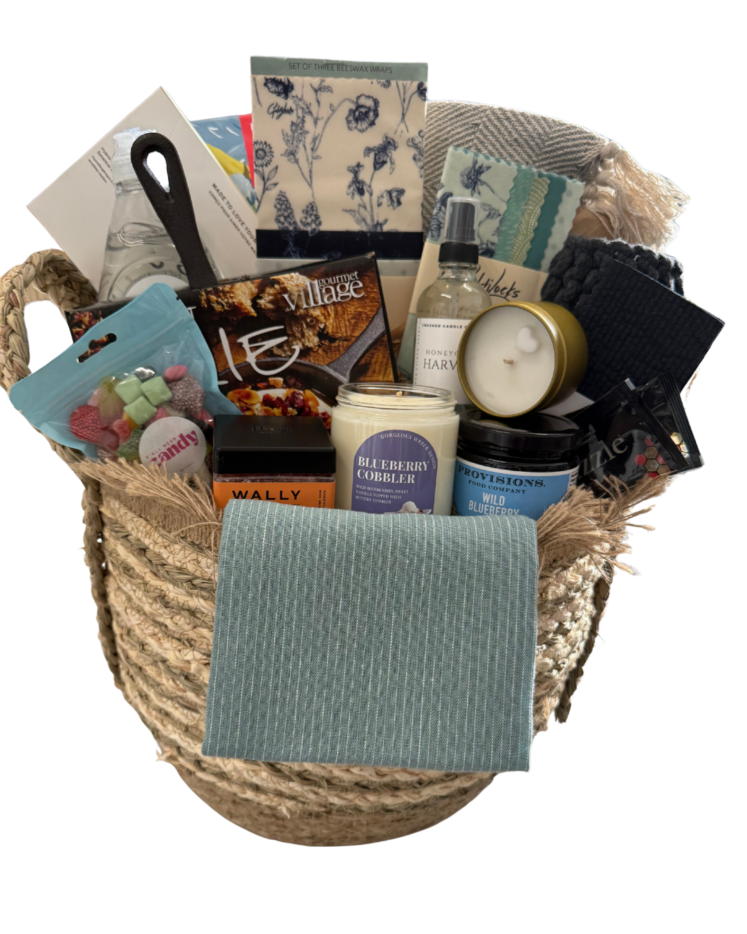 Gift basket with various items including candles, snacks, and a blanket on a white background