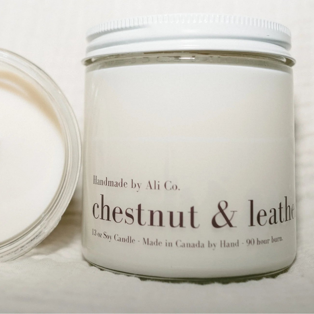 Candle with a visible wick and a white container labeled &