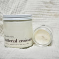 Jar of 'Buttered Croissant' candle on a textured surface